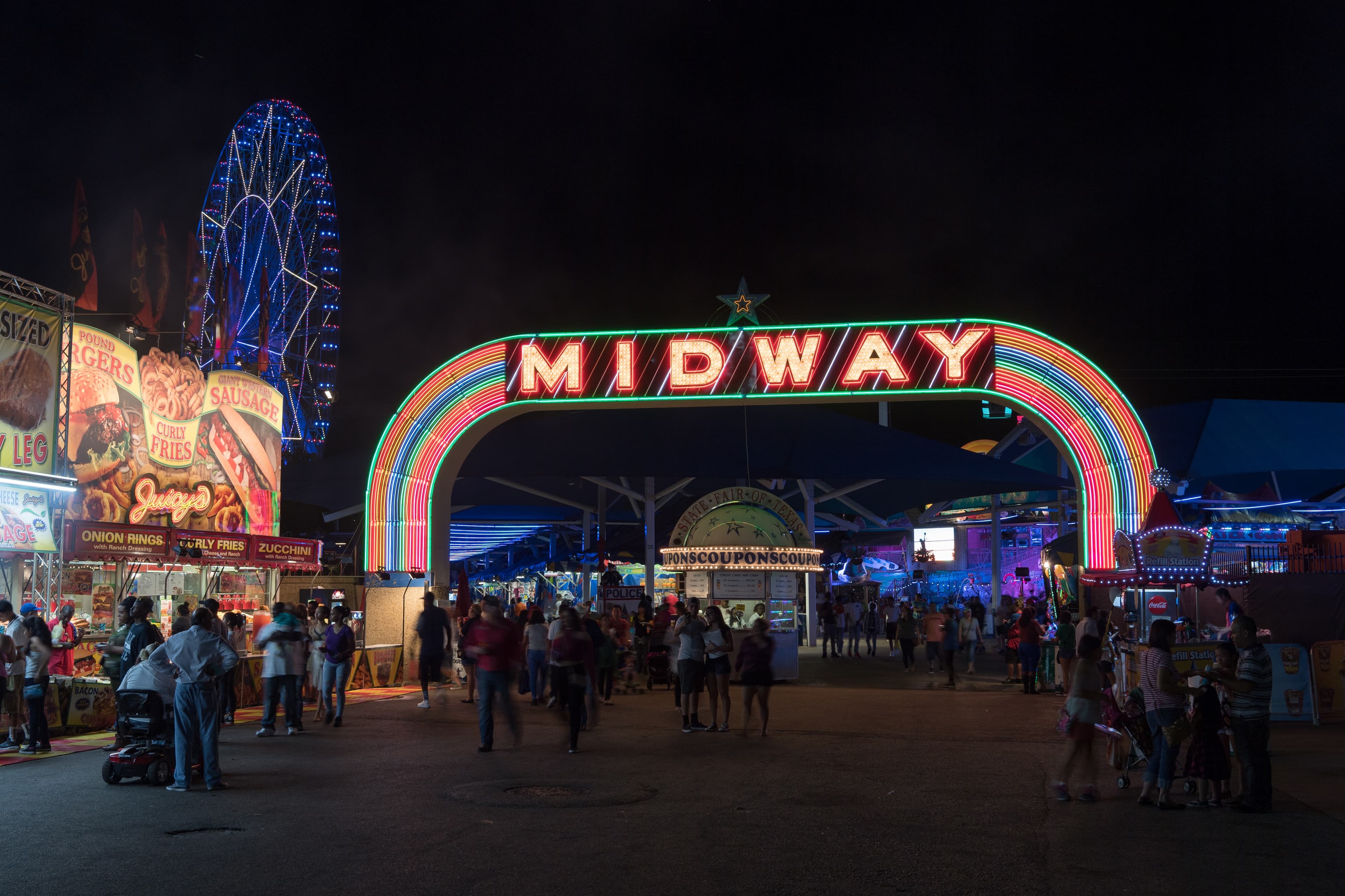File photo: Visitors walk beneath the illuminated Midway entrance.